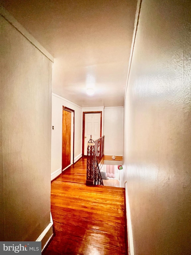 corridor with hardwood / wood-style flooring and ornamental molding