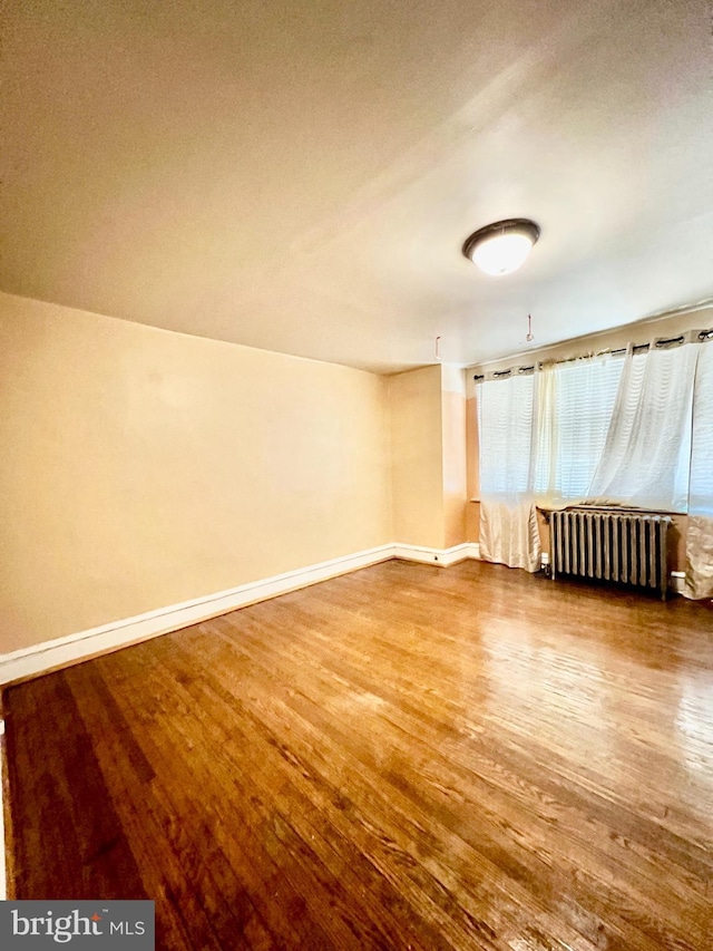 unfurnished room with hardwood / wood-style flooring and radiator heating unit