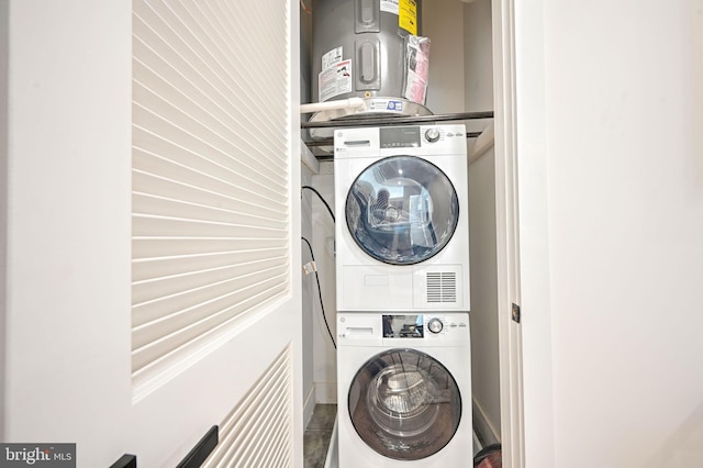 laundry room with electric water heater and stacked washer and dryer