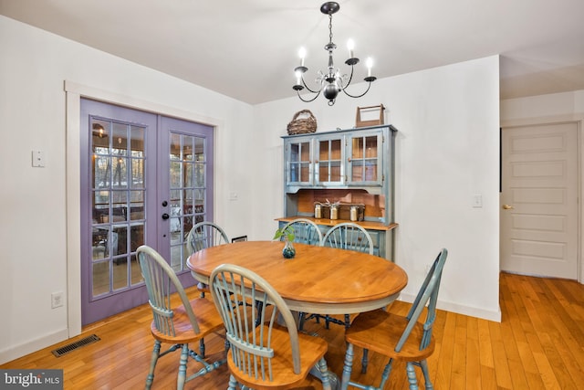 dining room with french doors, light hardwood / wood-style flooring, and a notable chandelier