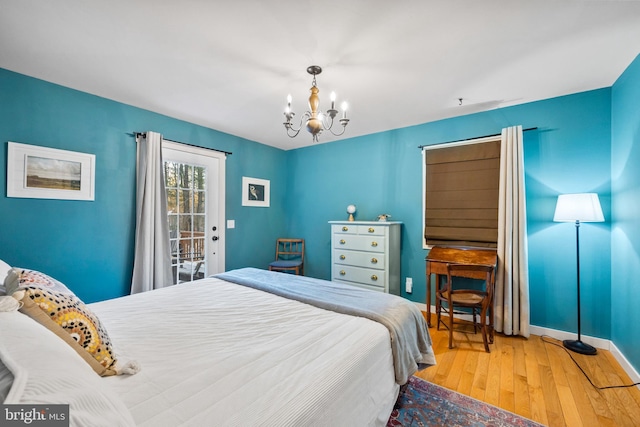 bedroom with access to outside, wood-type flooring, and a notable chandelier