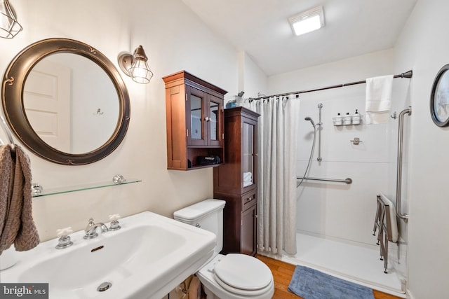 bathroom featuring toilet, curtained shower, hardwood / wood-style floors, and sink