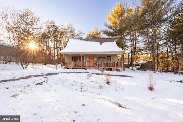 snow covered house featuring a porch