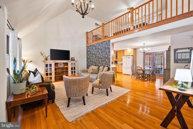 living room featuring high vaulted ceiling, light hardwood / wood-style floors, and a chandelier