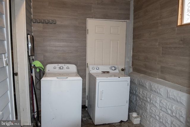 laundry room with washer and dryer and wooden walls