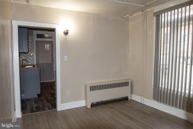 spare room with dark hardwood / wood-style flooring, radiator heating unit, and sink