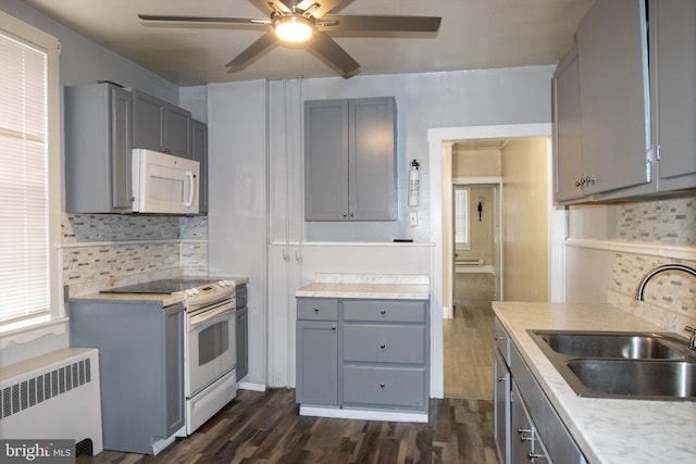 kitchen featuring backsplash, radiator, sink, and white appliances