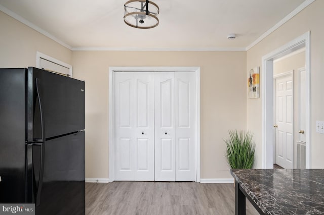 kitchen with black refrigerator, light hardwood / wood-style floors, and ornamental molding