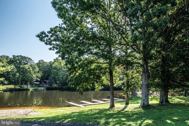 view of community featuring a lawn, a boat dock, and a water view