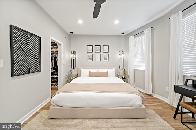 bedroom with ceiling fan, light wood-type flooring, a spacious closet, and a closet