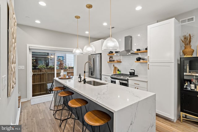 kitchen with white cabinets, island range hood, a center island with sink, and appliances with stainless steel finishes