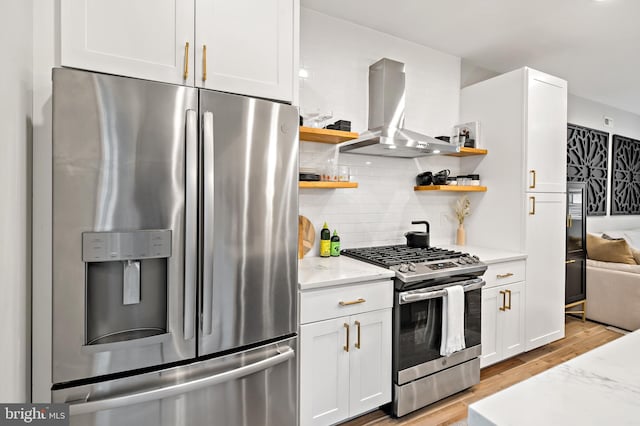 kitchen with light stone countertops, white cabinetry, island exhaust hood, and appliances with stainless steel finishes