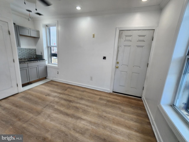 entryway featuring ceiling fan, a healthy amount of sunlight, light wood-type flooring, and crown molding