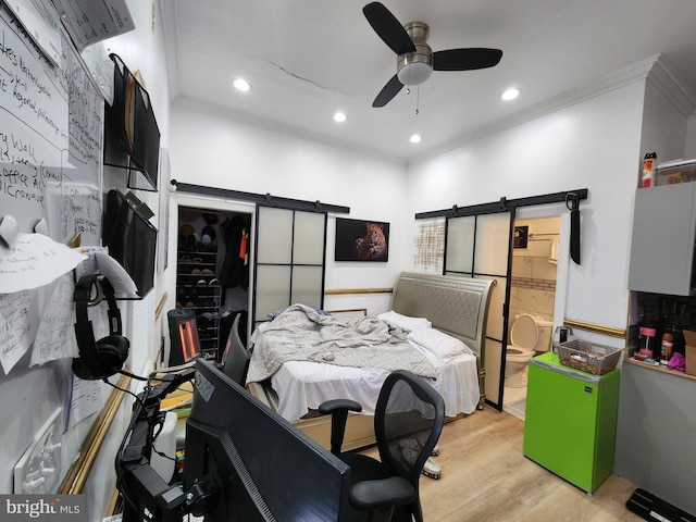 bedroom with refrigerator, crown molding, ceiling fan, a barn door, and light hardwood / wood-style floors