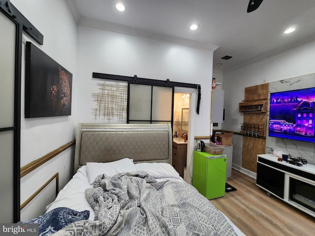 bedroom with ensuite bath, ceiling fan, light wood-type flooring, and ornamental molding