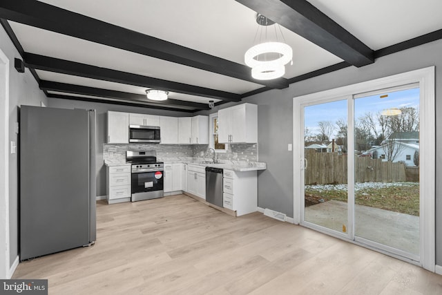 kitchen with appliances with stainless steel finishes, tasteful backsplash, decorative light fixtures, beamed ceiling, and white cabinets