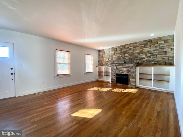 unfurnished living room featuring a stone fireplace and dark wood-type flooring