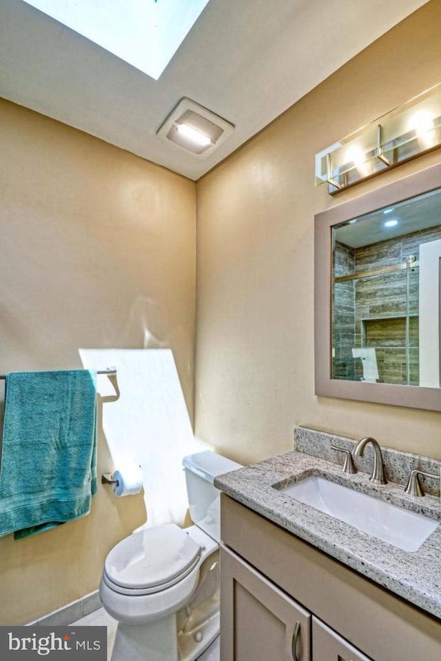 bathroom with tile patterned flooring, toilet, vanity, and walk in shower