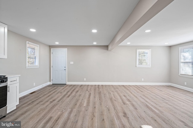 basement featuring a healthy amount of sunlight and light hardwood / wood-style floors