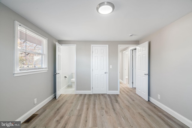 unfurnished bedroom with ensuite bathroom and light hardwood / wood-style floors