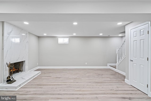 basement with a premium fireplace and light wood-type flooring