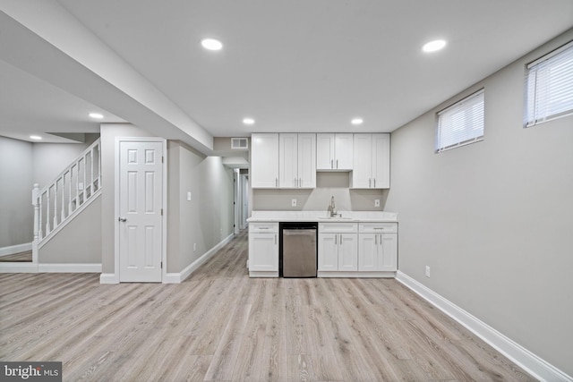 kitchen featuring white cabinets, light hardwood / wood-style floors, stainless steel dishwasher, and sink