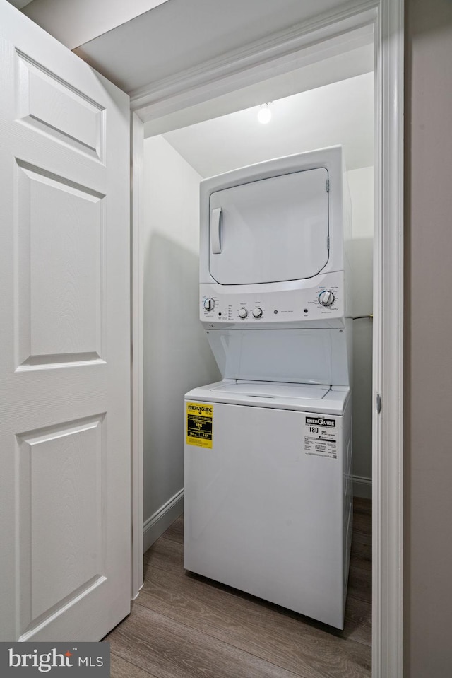 laundry room featuring hardwood / wood-style floors and stacked washer / drying machine