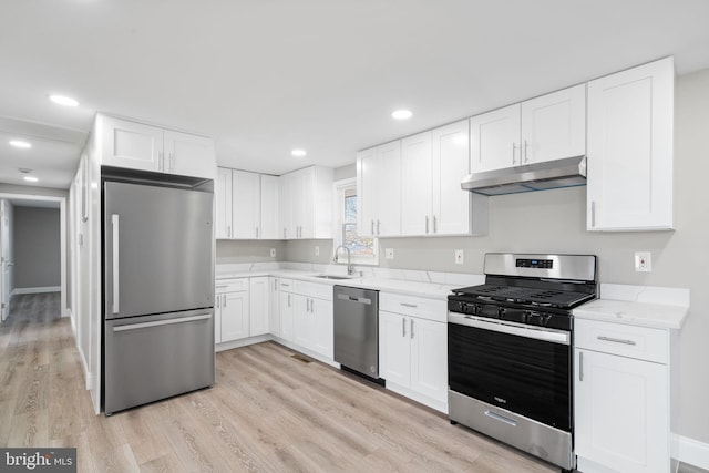 kitchen with white cabinetry, stainless steel appliances, light stone counters, and light hardwood / wood-style floors