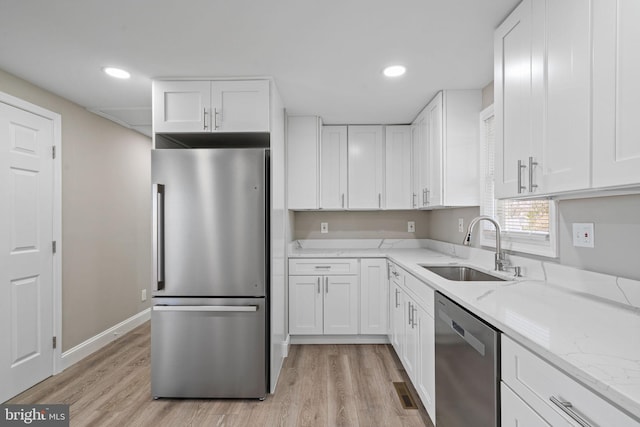 kitchen featuring white cabinets, sink, light stone countertops, and stainless steel appliances