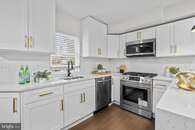 kitchen with light stone countertops, sink, dark hardwood / wood-style flooring, white cabinets, and appliances with stainless steel finishes