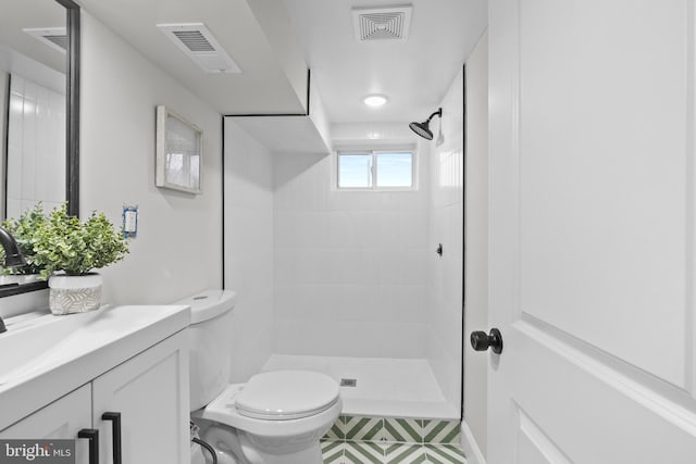 bathroom with tiled shower, vanity, and toilet