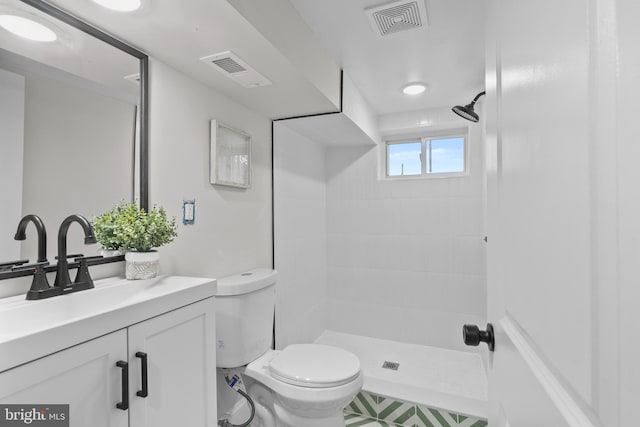 bathroom with tiled shower, vanity, and toilet