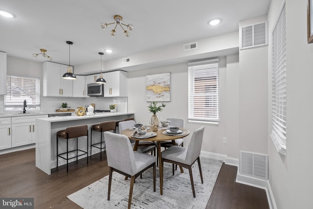 dining area with sink, a chandelier, and dark hardwood / wood-style floors