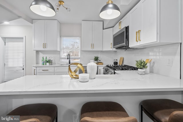 kitchen featuring a breakfast bar area, tasteful backsplash, white cabinets, and range