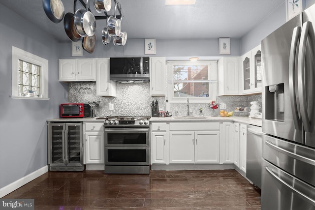 kitchen featuring beverage cooler, white cabinetry, stainless steel appliances, tasteful backsplash, and sink