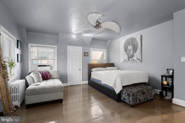 bedroom featuring radiator, ceiling fan, hardwood / wood-style floors, and multiple windows