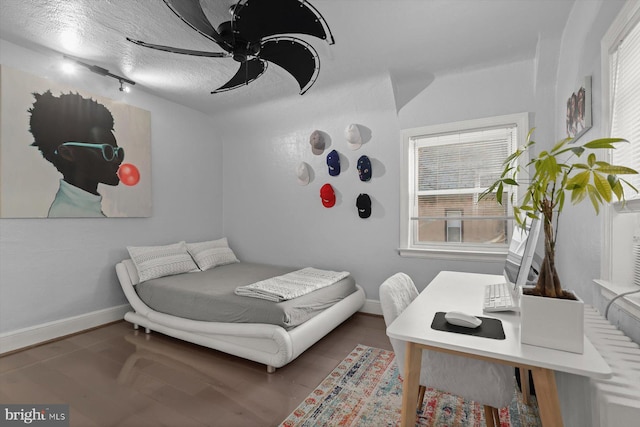 bedroom with ceiling fan, dark wood-type flooring, and a textured ceiling