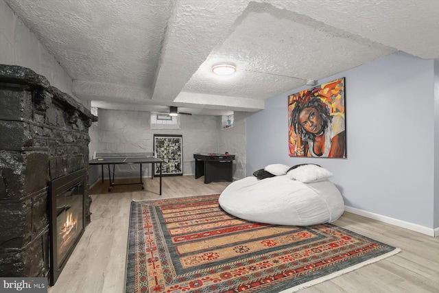 sitting room with light wood-type flooring, a fireplace, and a textured ceiling