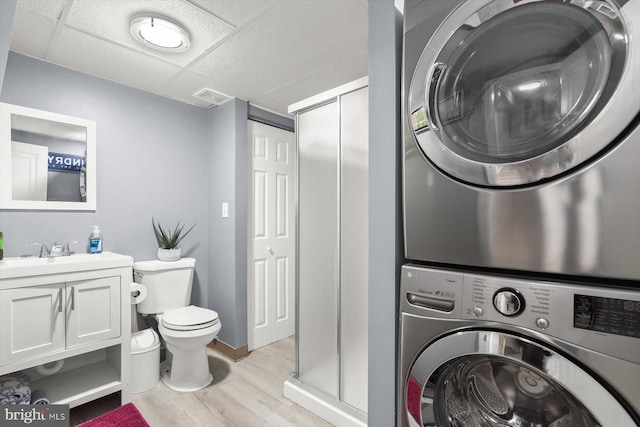 clothes washing area with sink, stacked washer / drying machine, and light hardwood / wood-style flooring