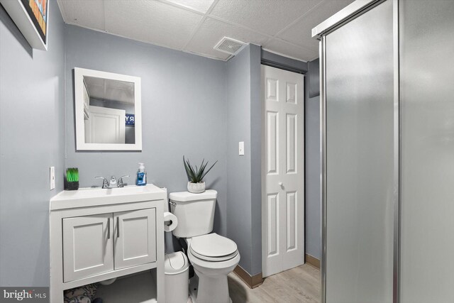 bathroom featuring toilet, vanity, a paneled ceiling, and hardwood / wood-style floors