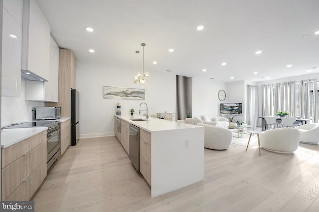 kitchen with backsplash, sink, light hardwood / wood-style flooring, appliances with stainless steel finishes, and decorative light fixtures