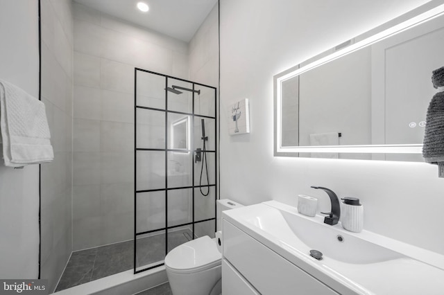 bathroom featuring a tile shower, vanity, and toilet