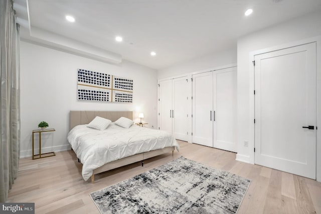 bedroom featuring light hardwood / wood-style floors and multiple closets