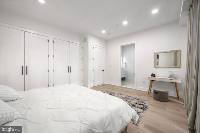 bedroom with ensuite bath, two closets, and light wood-type flooring