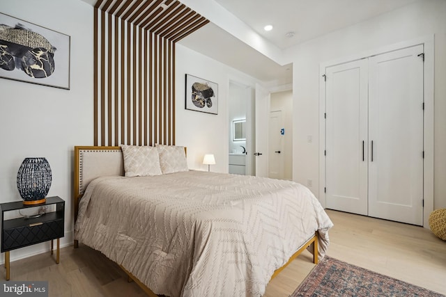 bedroom with ensuite bathroom and light hardwood / wood-style floors