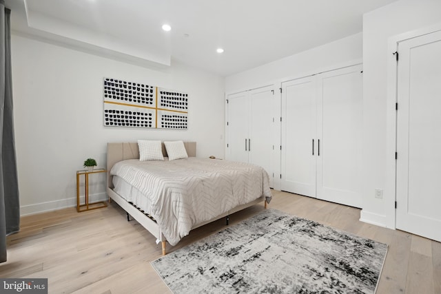 bedroom featuring multiple closets and light wood-type flooring