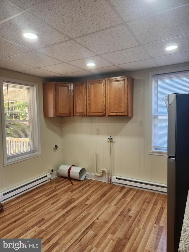 laundry area featuring cabinets, baseboard heating, and light hardwood / wood-style flooring