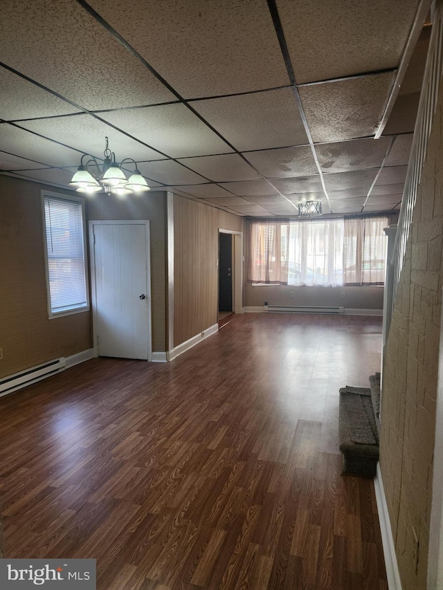 spare room featuring hardwood / wood-style floors, an inviting chandelier, baseboard heating, and a drop ceiling