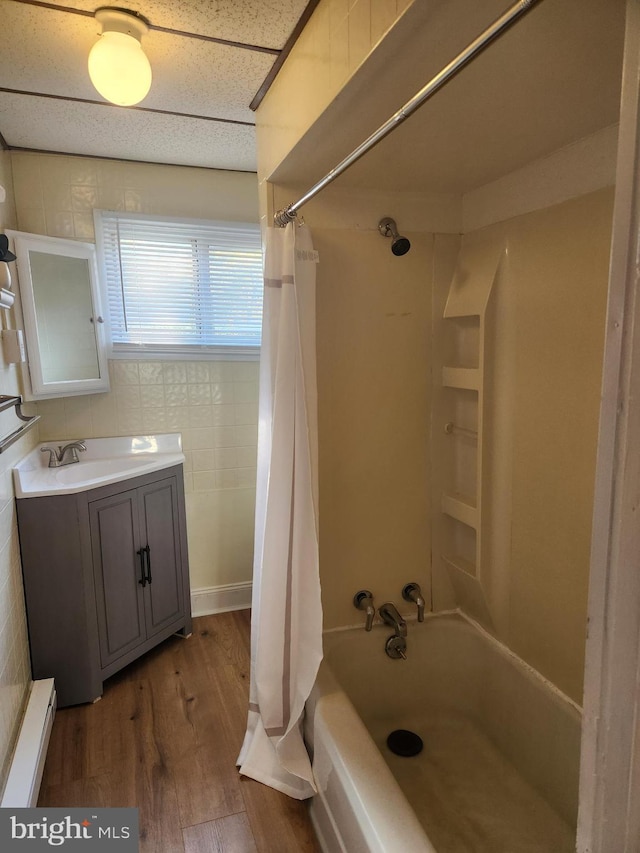 bathroom featuring hardwood / wood-style floors, shower / bath combo, vanity, and a baseboard heating unit