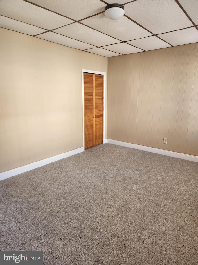 unfurnished room featuring carpet and a drop ceiling